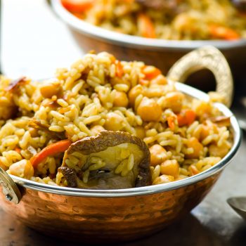 vegetarian pilaf with chick-pea and mushrooms in a copper Indian bowl. selective focus